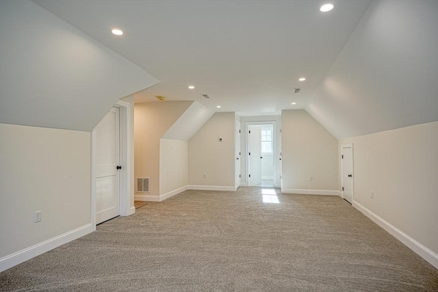 additional living space featuring light colored carpet and vaulted ceiling