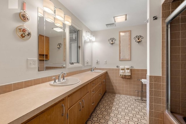 16 Wadsworth Ln, Dartmouth, MA 02748 - bathroom featuring tile walls, tiled shower, double vanity, a wainscoted wall, and tile patterned flooring