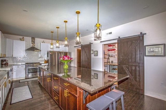 56 Otis-Tolland Rd, Blandford, MA 01008 - kitchen with a barn door, wall chimney exhaust hood, stainless steel appliances, dark wood-type flooring, and decorative backsplash