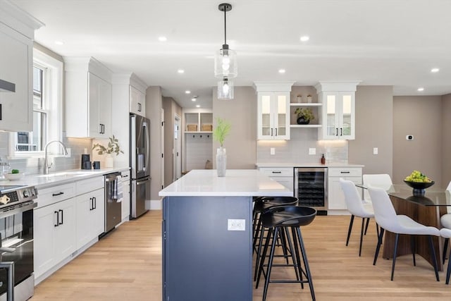 110 Fayette Unit 110, Watertown, MA 02472 - kitchen featuring a kitchen breakfast bar, a kitchen island, wine cooler, stainless steel appliances, and light wood finished floors