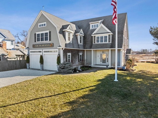 shingle-style home featuring an attached garage, a gambrel roof, a shingled roof, concrete driveway, and a front lawn