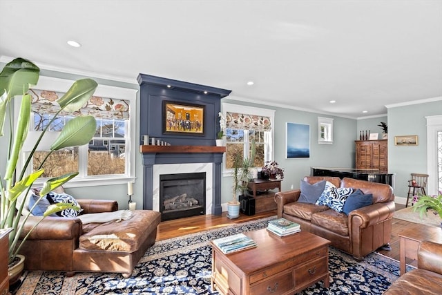 living area with crown molding, baseboards, a premium fireplace, recessed lighting, and wood finished floors