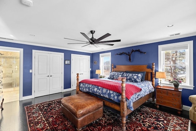 bedroom with baseboards, ceiling fan, multiple closets, ornamental molding, and wood finished floors