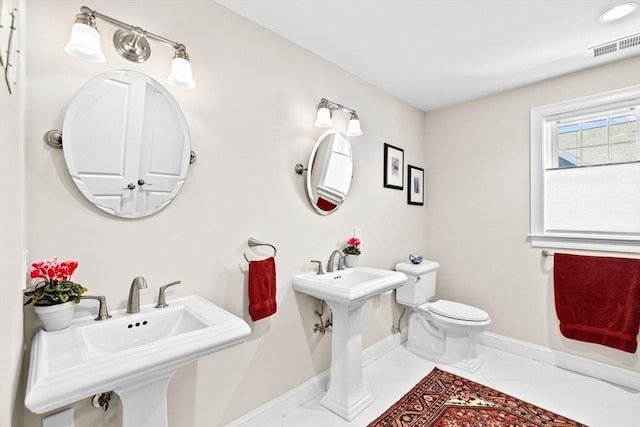 bathroom with tile patterned flooring, visible vents, baseboards, toilet, and a sink