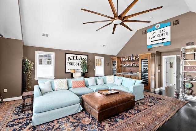 living room with indoor wet bar, visible vents, and high vaulted ceiling