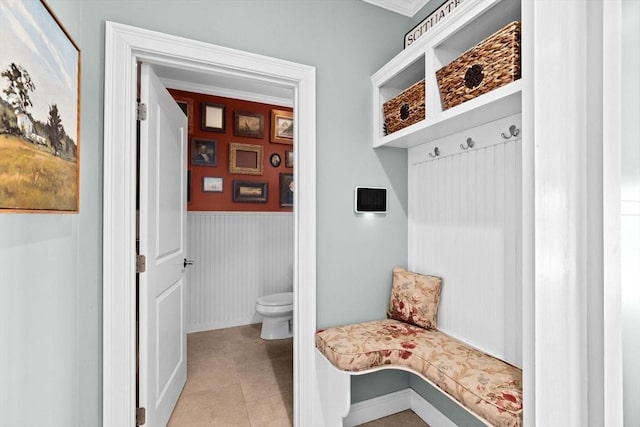 mudroom with light tile patterned floors and a wainscoted wall