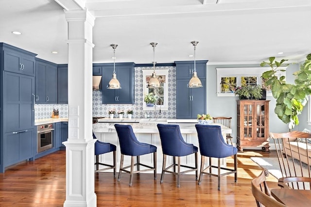 kitchen featuring a kitchen bar, blue cabinets, ornate columns, and oven