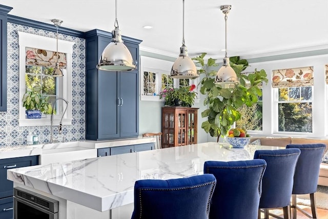 kitchen featuring ornamental molding, blue cabinets, light stone countertops, and a healthy amount of sunlight