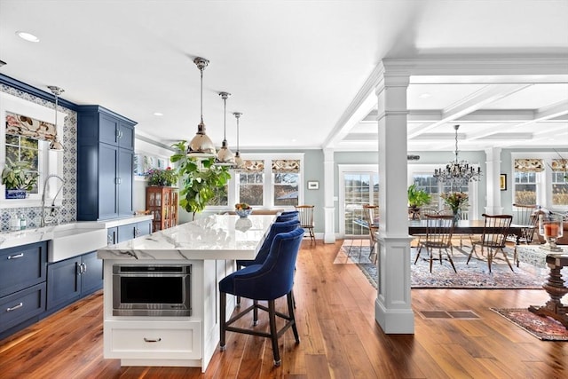 kitchen featuring oven, blue cabinets, ornate columns, and a sink