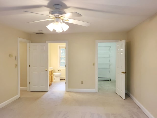 unfurnished bedroom featuring a spacious closet, a baseboard radiator, ensuite bath, light colored carpet, and ceiling fan