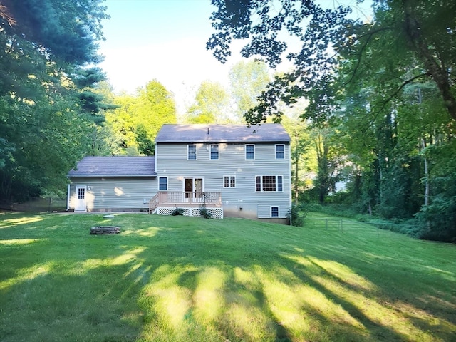 back of house with a wooden deck, a lawn, and an outdoor fire pit