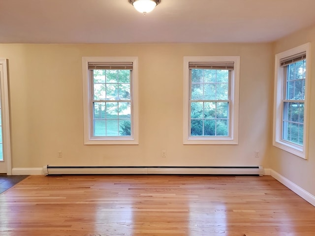 spare room featuring baseboard heating and light hardwood / wood-style floors