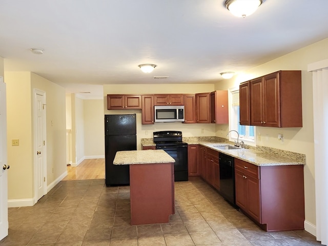 kitchen featuring black appliances, light stone counters, a center island, and sink