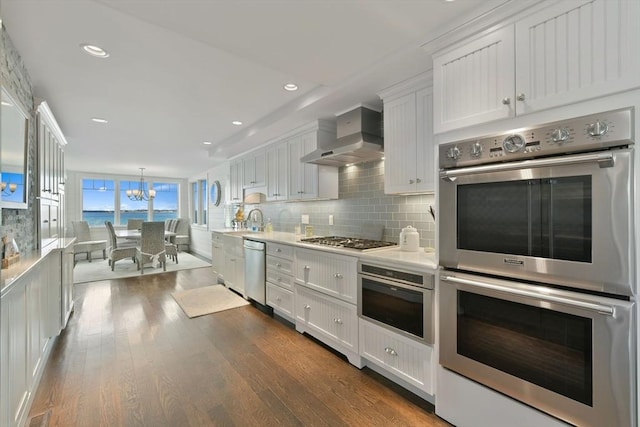 kitchen with white cabinetry, wall chimney range hood, dark hardwood / wood-style flooring, stainless steel appliances, and backsplash