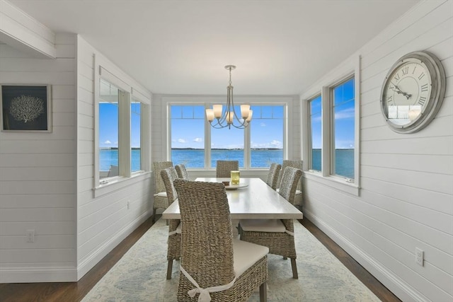 dining room with a water view, dark wood-type flooring, and an inviting chandelier