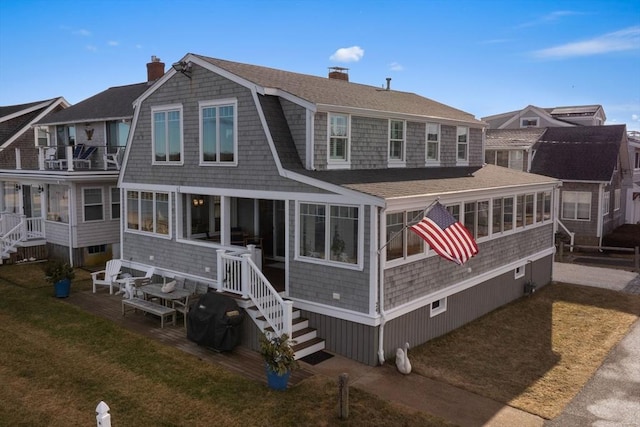 rear view of house with a yard and a sunroom