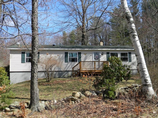 manufactured / mobile home with a front lawn, a wooden deck, and a chimney