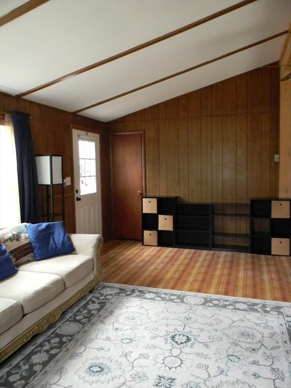 unfurnished living room with wooden walls, wood finished floors, and lofted ceiling