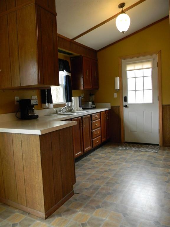 kitchen with light countertops, wainscoting, a sink, and lofted ceiling