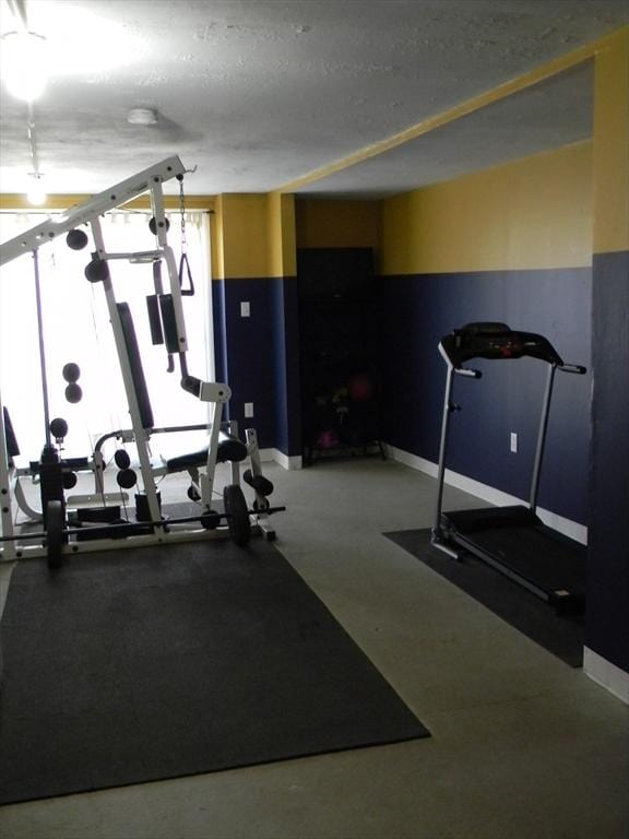 exercise room with a textured ceiling and baseboards