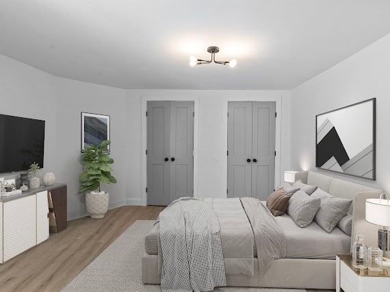 bedroom featuring multiple closets and light hardwood / wood-style flooring