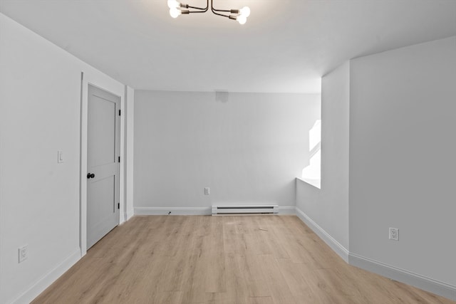 unfurnished room featuring light wood-type flooring, baseboard heating, and a notable chandelier