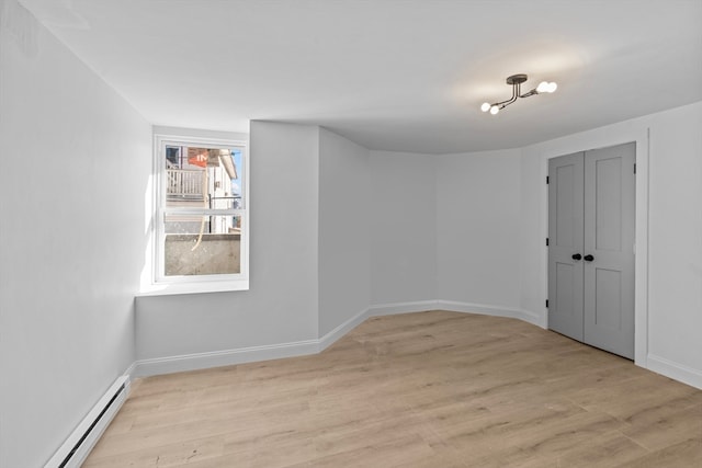 empty room featuring a baseboard radiator and light hardwood / wood-style floors