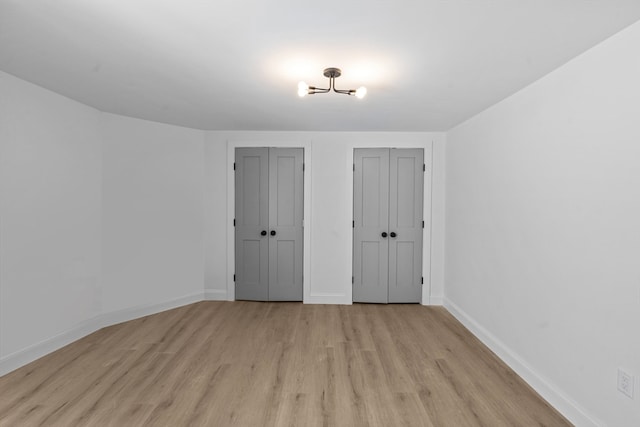 unfurnished bedroom with two closets and light hardwood / wood-style flooring