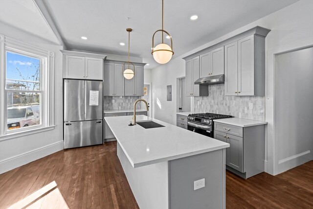 kitchen with decorative backsplash, appliances with stainless steel finishes, sink, dark hardwood / wood-style floors, and hanging light fixtures