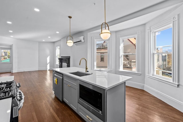 kitchen with pendant lighting, a wall mounted air conditioner, sink, gray cabinets, and stainless steel appliances