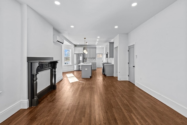 living room featuring a wall mounted AC, sink, and dark hardwood / wood-style floors