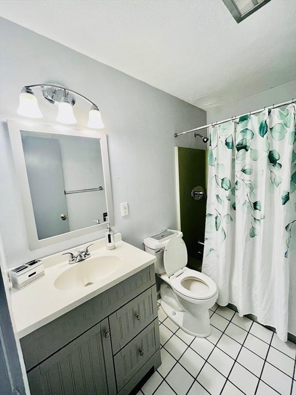 bathroom featuring walk in shower, tile patterned floors, vanity, and toilet