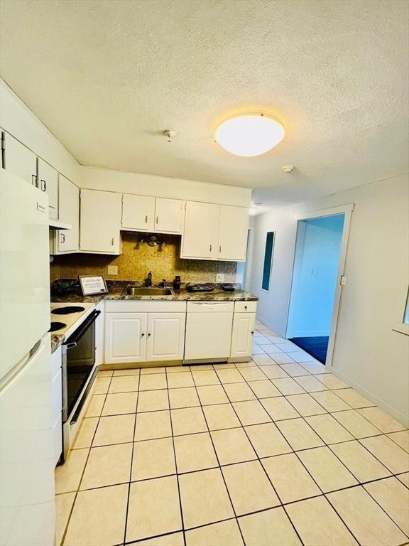 kitchen with light tile patterned flooring, tasteful backsplash, white cabinets, exhaust hood, and white appliances