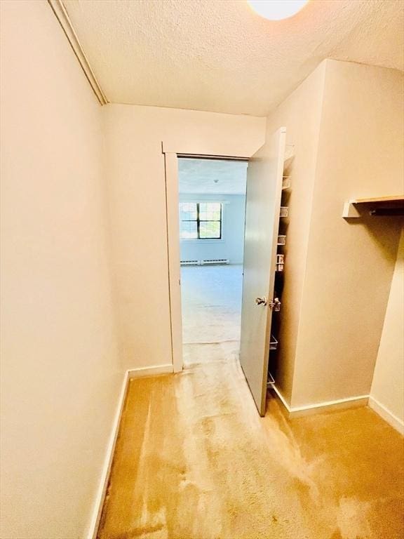 hallway featuring light carpet and a textured ceiling