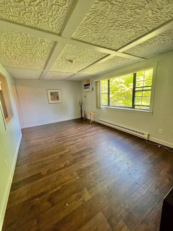 unfurnished room featuring an AC wall unit, a baseboard radiator, and dark hardwood / wood-style floors