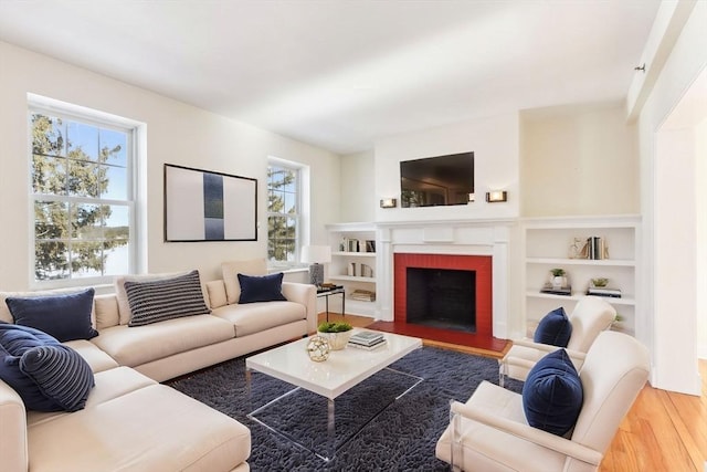 living room featuring a brick fireplace and wood finished floors