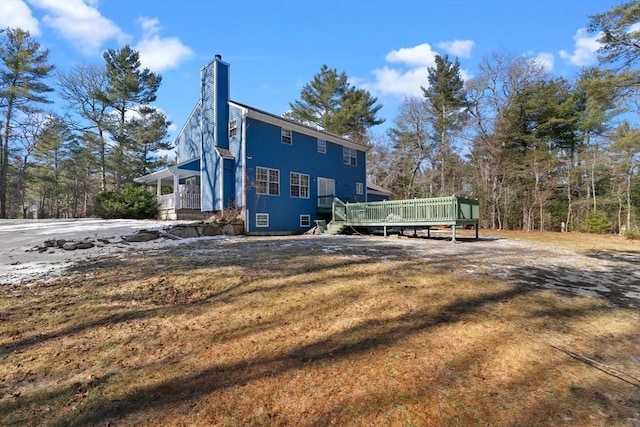 exterior space with a deck, a lawn, and a chimney