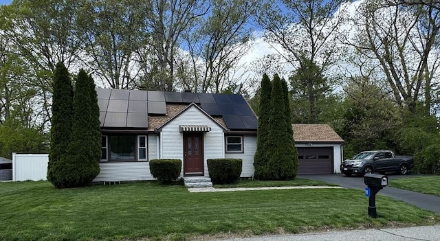 view of front of property featuring roof mounted solar panels, a front lawn, a garage, and driveway