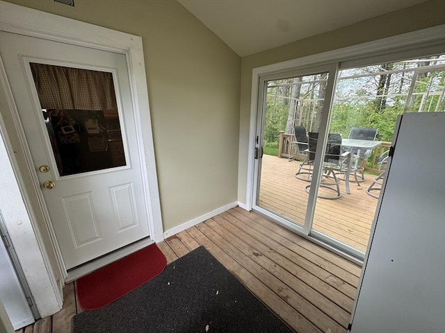 doorway to outside with wood-type flooring, vaulted ceiling, and baseboards
