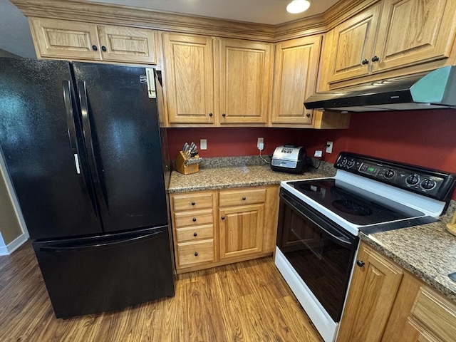 kitchen featuring freestanding refrigerator, electric stove, under cabinet range hood, light wood-type flooring, and light stone counters
