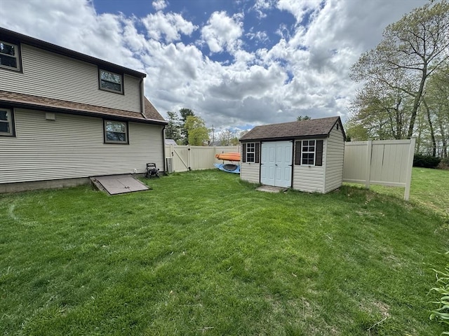 view of yard featuring a storage unit, an outdoor structure, and a gate