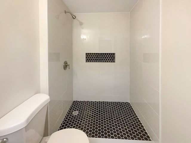 bathroom with a tile shower and toilet