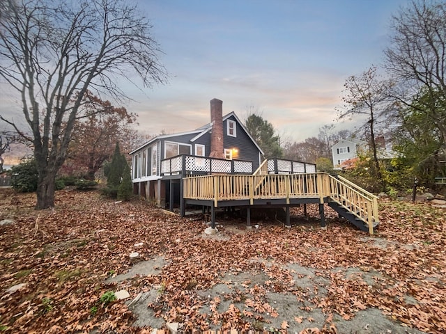 back house at dusk featuring a deck and a sunroom