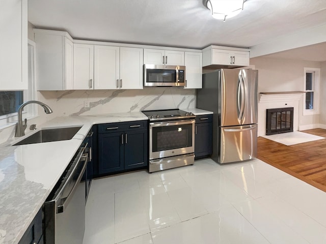 kitchen with tasteful backsplash, stainless steel appliances, sink, light hardwood / wood-style flooring, and white cabinets