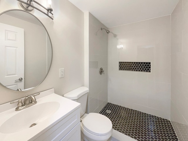 bathroom featuring a tile shower, vanity, and toilet