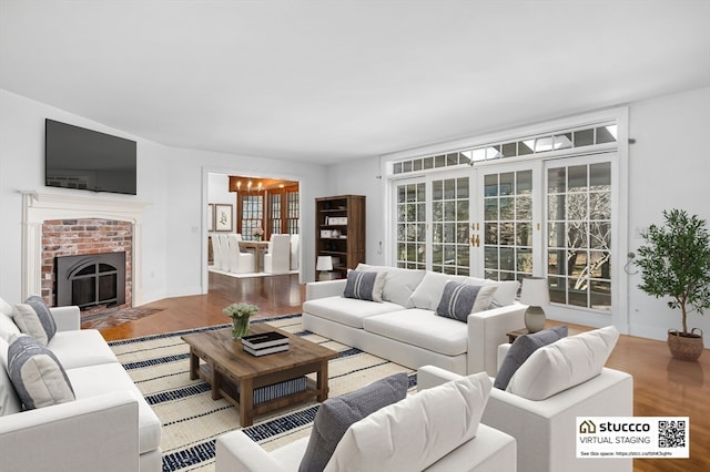 living room featuring a fireplace, french doors, hardwood / wood-style flooring, and a chandelier