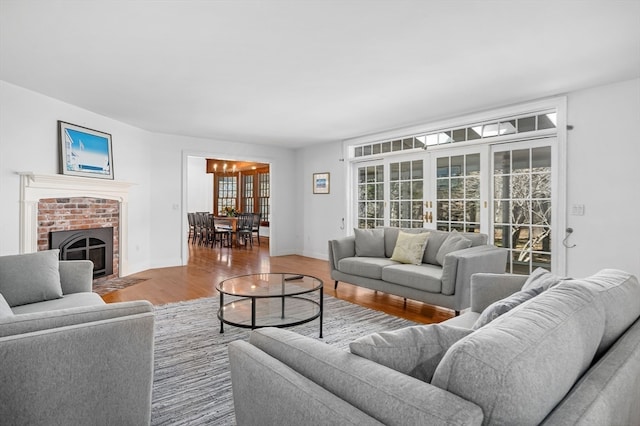 living room featuring light hardwood / wood-style floors, french doors, a fireplace, and an inviting chandelier