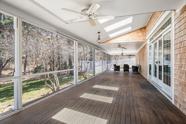 unfurnished sunroom with lofted ceiling with skylight, ceiling fan, and a healthy amount of sunlight