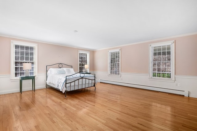 bedroom featuring crown molding, a baseboard heating unit, and light hardwood / wood-style floors