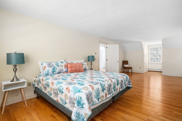 bedroom with light hardwood / wood-style flooring and a baseboard heating unit